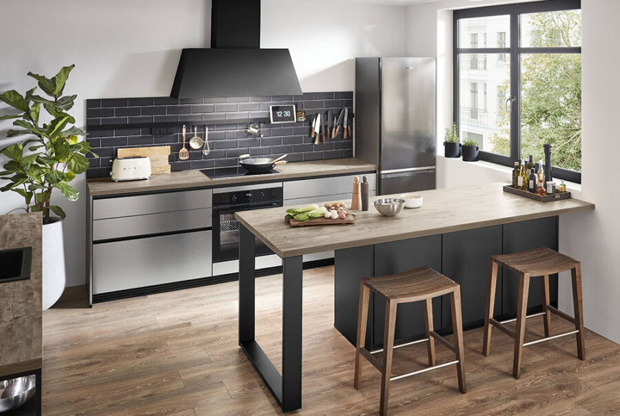 Cuisine moderne avec îlot central bois, tabourets, crédence noire, électroménager inox et grande fenêtre