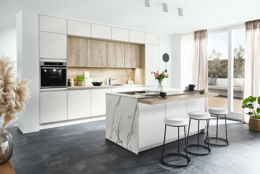 Cuisine moderne avec îlot central en marbre blanc, tabourets design et armoires bicolores blanc et bois naturel