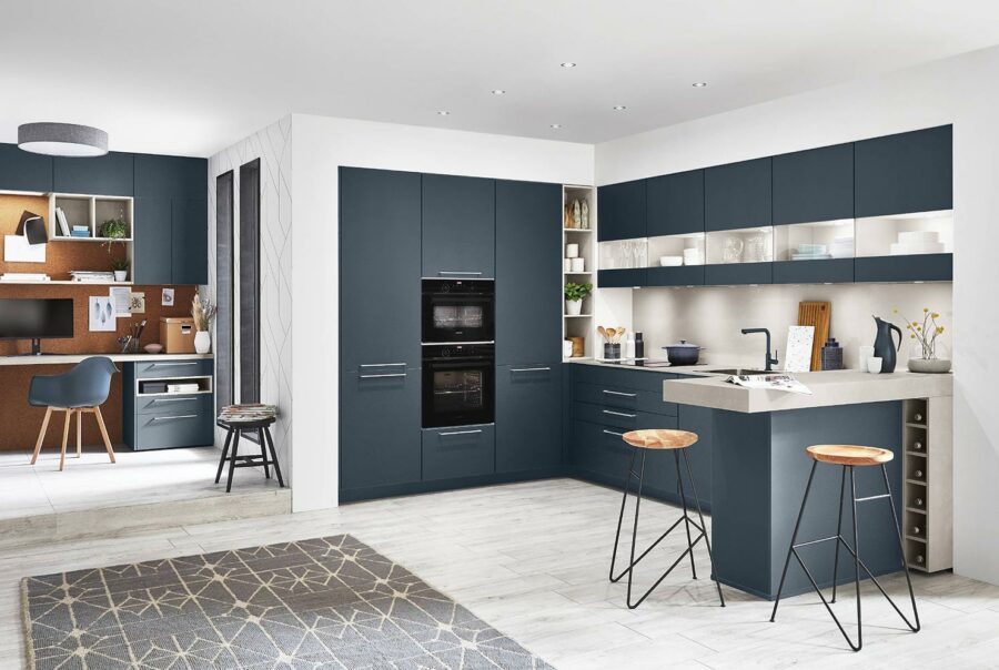Cuisine moderne avec façades bleu marine, îlot central blanc, tabourets en bois et espace bureau intégré