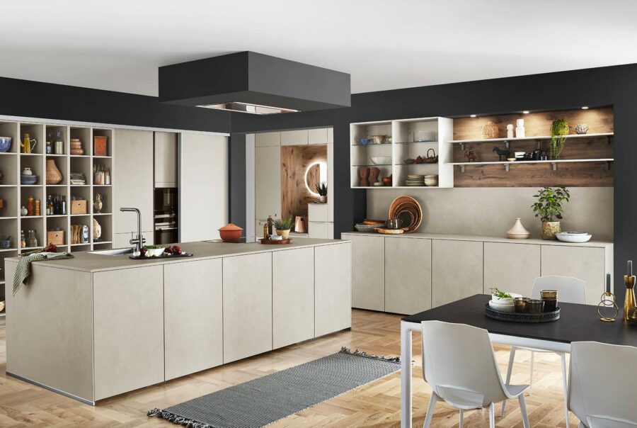 Cuisine moderne avec îlot central beige, étagères ouvertes, plan de travail noir et salle à manger intégrée