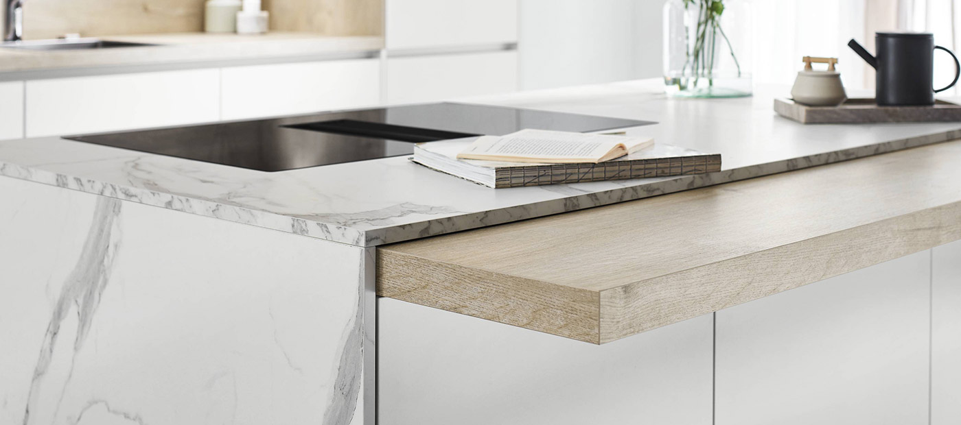 Cuisine moderne avec îlot central en marbre blanc, plaque de cuisson intégrée et tiroir en bois ouvert