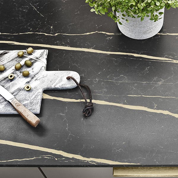 Plan de travail en marbre noir veiné d'or avec planche à découper, olives, couteau et plante verte décorative