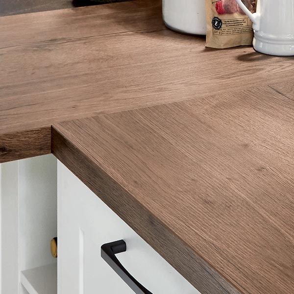 Plan de travail en bois avec finition chêne naturel dans une cuisine moderne avec meuble blanc en arrière-plan