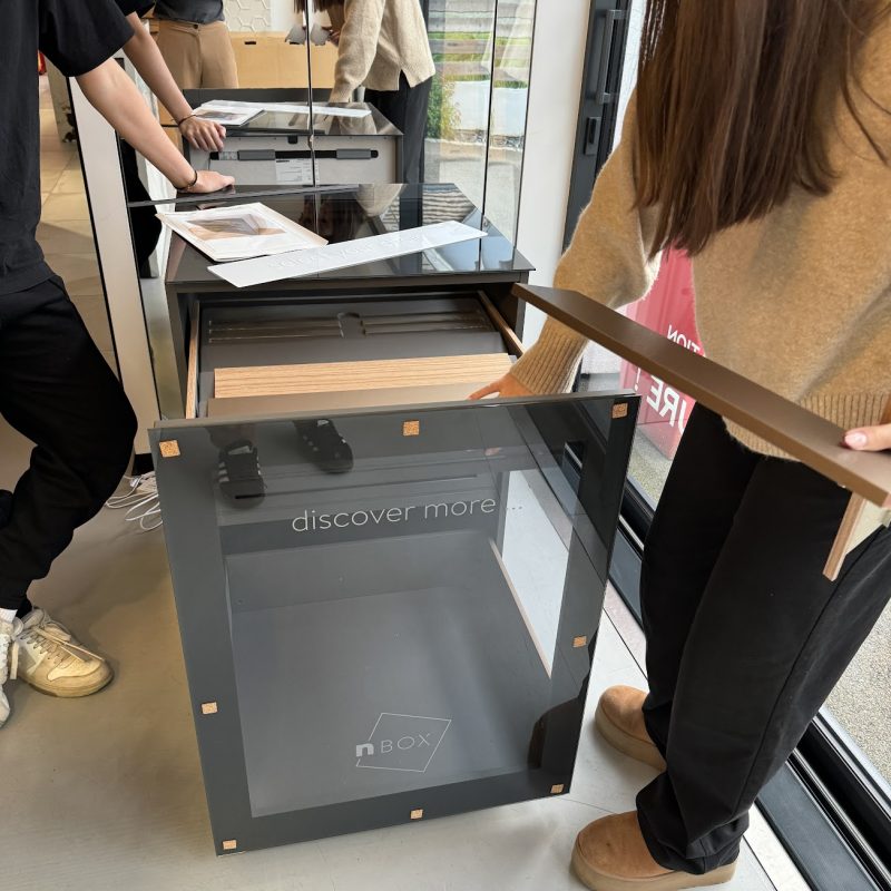 Personnes utilisant un écran tactile interactif nBox dans un showroom moderne avec discover more affiché