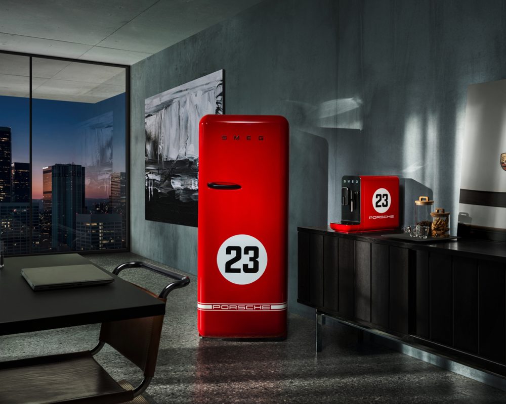 Réfrigérateur SMEG rouge Porsche numéro 23 dans cuisine moderne avec vue urbaine nocturne par baie vitrée