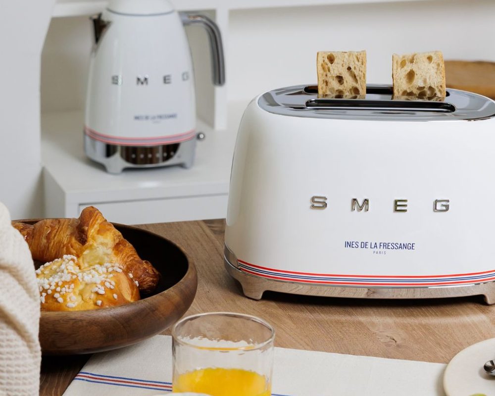 Grille-pain blanc SMEG avec pain grillé, petit-déjeuner avec croissants, jus d'orange et bouilloire sur plan de travail